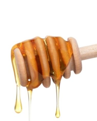 Czy miód jest szkodliwy dla dzieci? Na zdjęciu miód spływający po drewnianym przyrządzie.