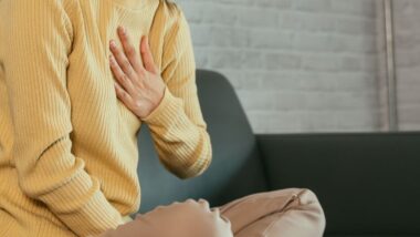 Dziewczyna trzyma dłoń na przełyku. Jakie są sposoby na refluks u dzieci?