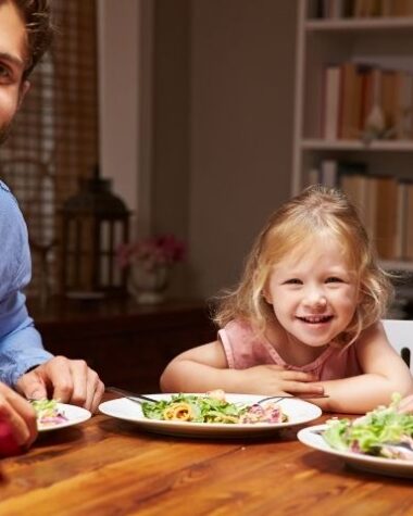 Szczęśliwa rodzina spożywa wspólnie kolacje.