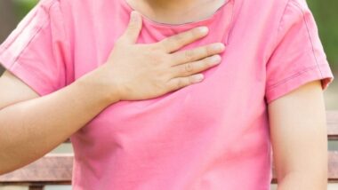Kobieta trzyma się za okolice przełyku, bo odczuwa refluks. Co w przypadku refluksu u 2-letniego dziecka?