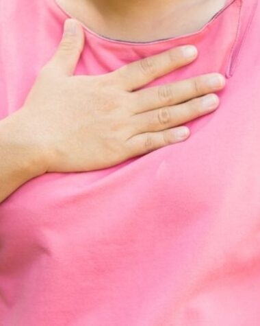 Kobieta trzyma się za okolice przełyku, bo odczuwa refluks. Co w przypadku refluksu u 2-letniego dziecka?