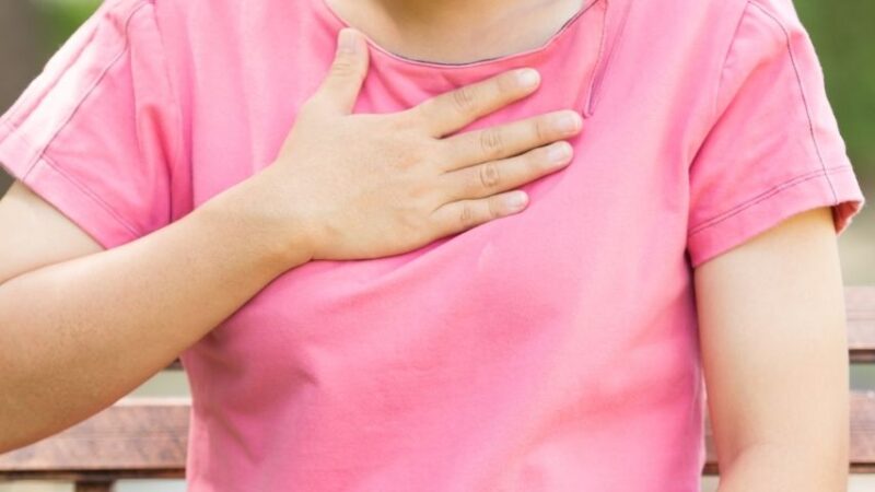 Kobieta trzyma się za okolice przełyku, bo odczuwa refluks. Co w przypadku refluksu u 2-letniego dziecka?