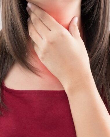 Kobieta trzyma się za gardło, bo odczuwa refluks. A co, jeśli refluks odczuwa 3-letnie dziecko?