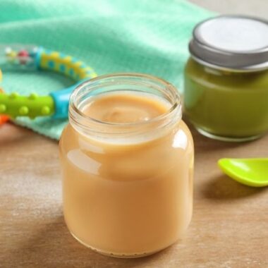 Kolorowe słoiczki dla dzieci ze smacznym pożywieniem ułożone na stole.